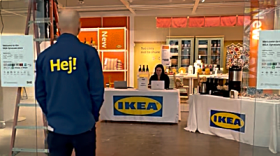 A man walking into the entrance of an IKEA store with table and merchandise on displays behind