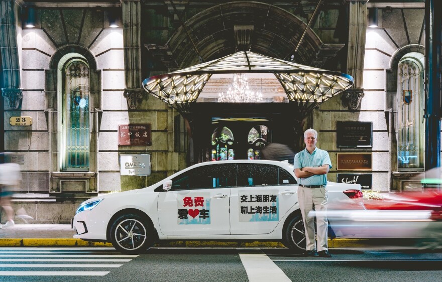 NPR reporter Frank Langfitt stands next to the taxi he used to give free rides to strangers in Shanghai to investigate shifts in China's social and political paradigm.