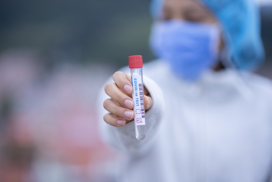 A healthcare worker holds a COVID-19 test tube