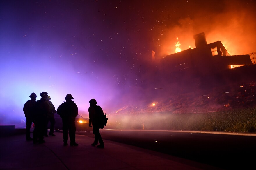 Firefighters in Thousand Oaks monitor a house fully engulfed by fire.