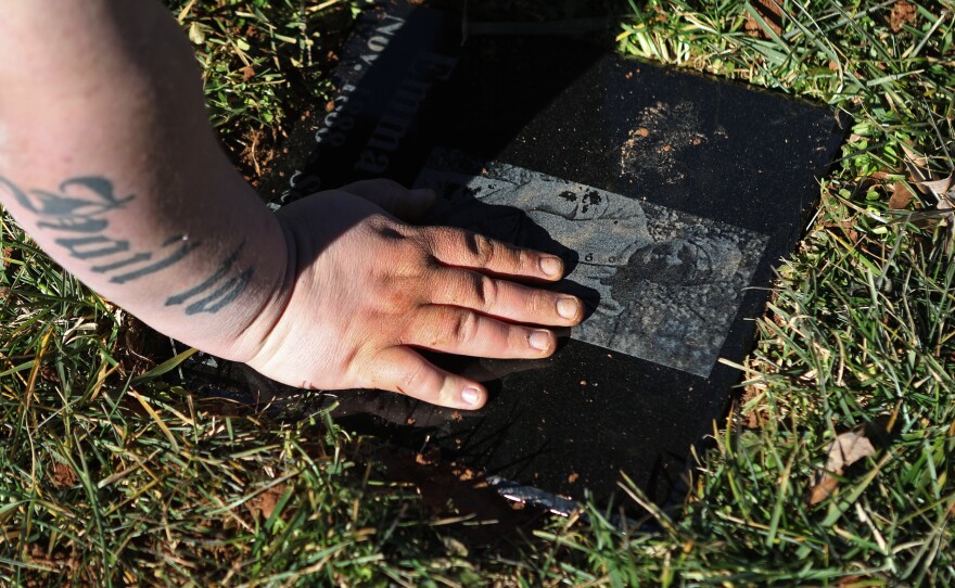 Cody places a stone on a distant family member's gravesite.