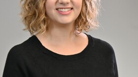 Woman in a black, long-sleeve shirt posing on a gray background.