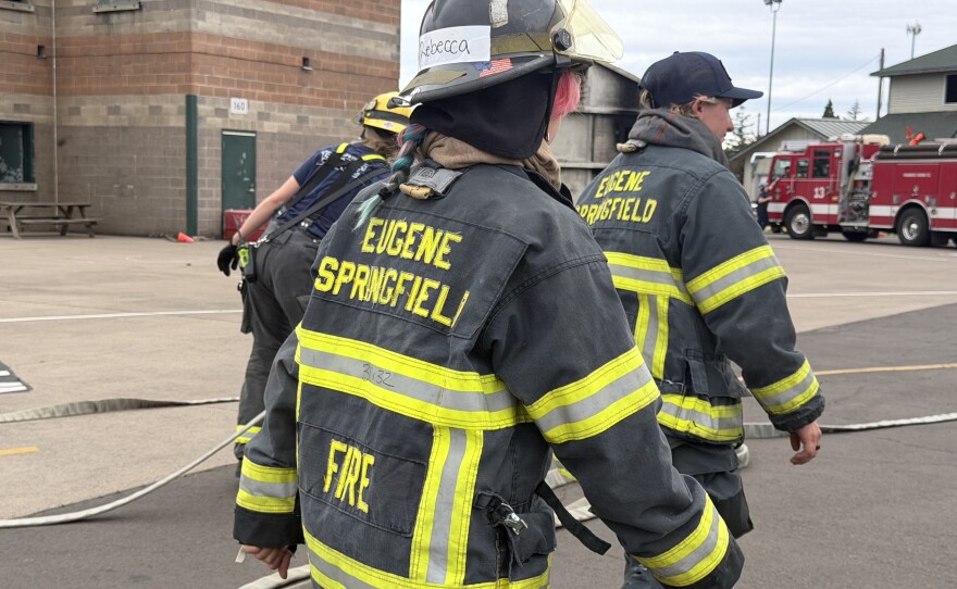 Two campers and an instructor walk back to the hose deployment station, June 25, 2026.