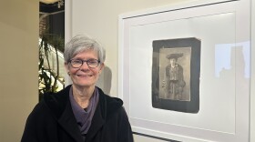 Patricia Watkins stands next to a portrait photograph of Catherine Higgins Watkins, her great-grandmother who was institutionalized at the Buffalo State Asylum.
