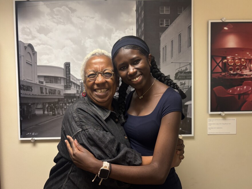 A young girl and an older woman stand embracing each other. 