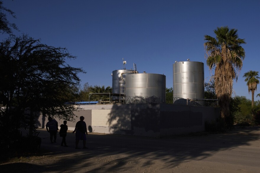 Residents at Oasis Mobile Home Park walk past water tanks in Thermal, Calif., Tuesday, April 15, 2025.
