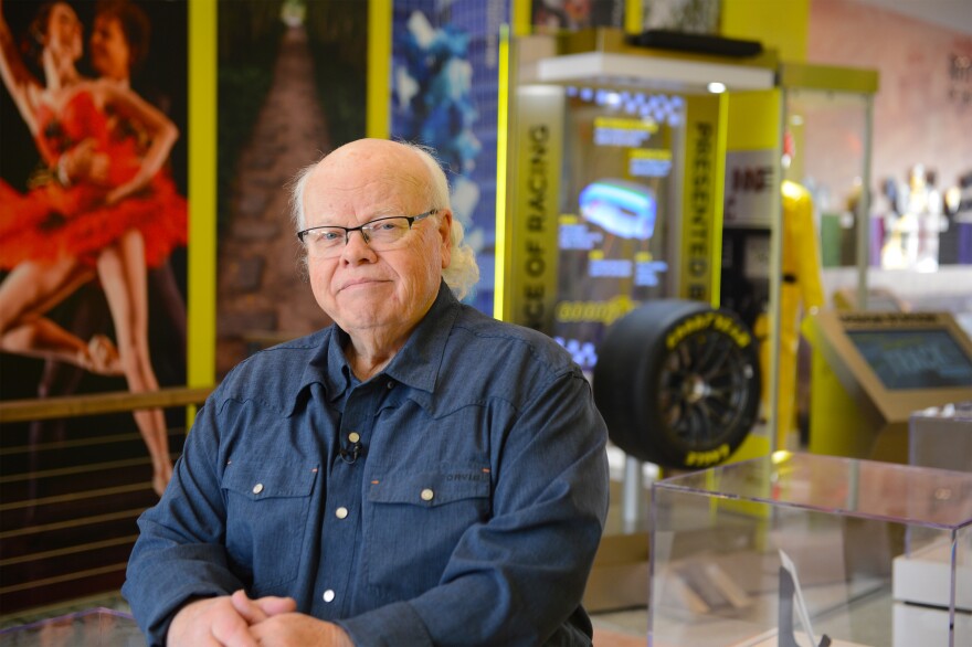 A man in a blue shirt poses in front of museum exhibits