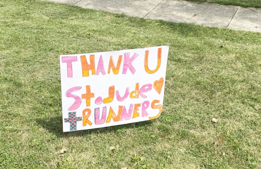 A handmade sign on grass thanks participants in a St. Jude run, with a sidewalk visible in the background.