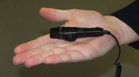 A police officer displays an example of a body camera. Photo: Renata Sago, WMFE