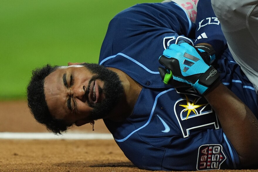 baseball player in blue tampa bay rays uniform hold his hand in pain 