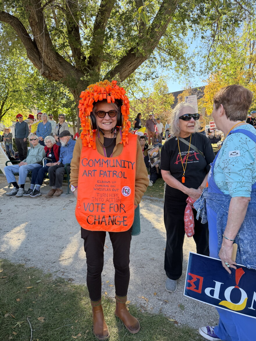 A woman wears a sign as other protesters gather behind her.