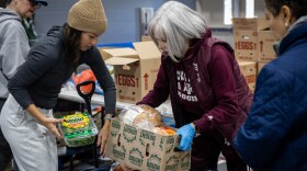 Volunteers Brooke Marshall, left, and Gwynn Beeler, center, help load up groceries for an attendee of the Central Texas Food Bank food distribution on Tuesday, Nov. 11, 2025, at George Morales Dove Springs Recreation Center in Austin. Food bank staff reported a 50% surge in demand at food distributions as SNAP benefits are cut. Michael Minasi / KUT News