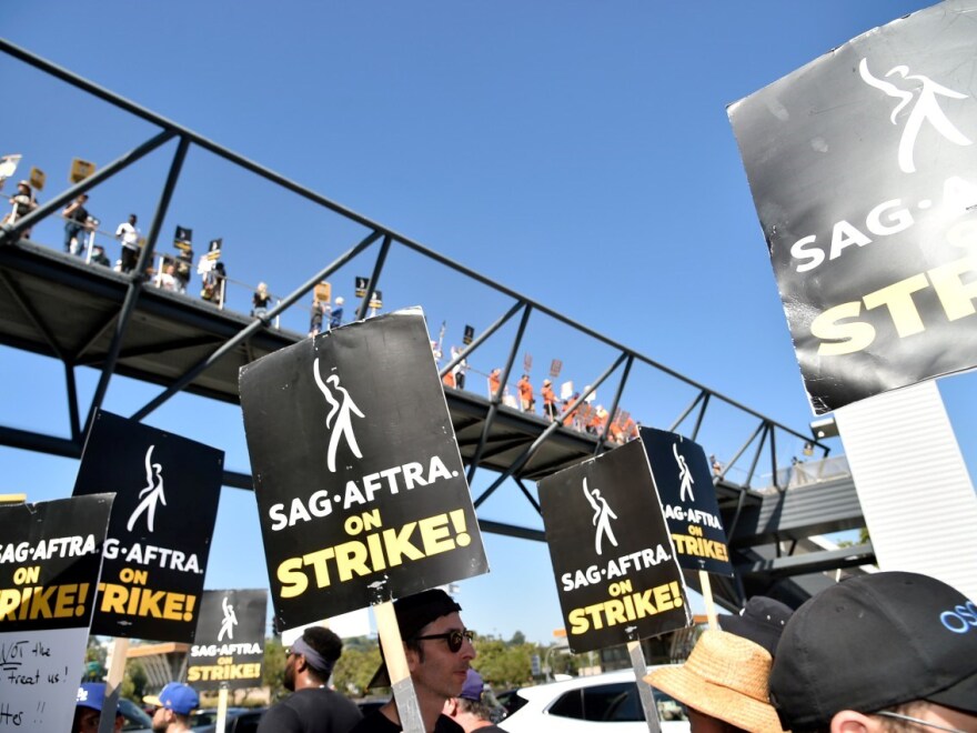 Picketers carry signs on the picket line outside Universal Studios on Friday, Aug. 4, 2023, in Universal City, Calif. The actors strike comes more than two months after screenwriters began striking in their bid to get better pay and working condition.