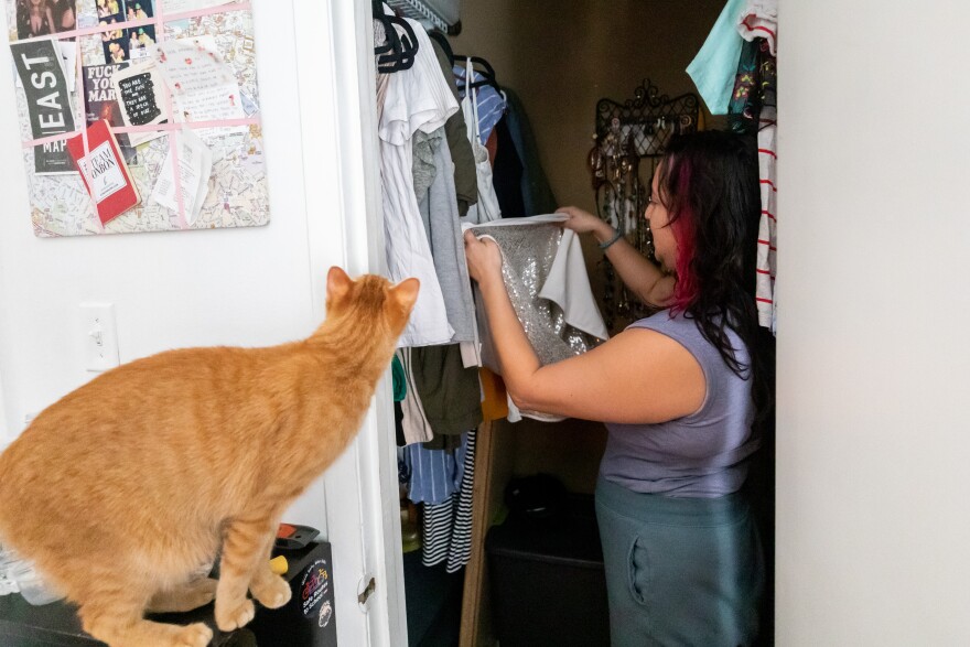 Amanda Phillips' cat looks on as she browses through her favorite dresses to wear on dates.