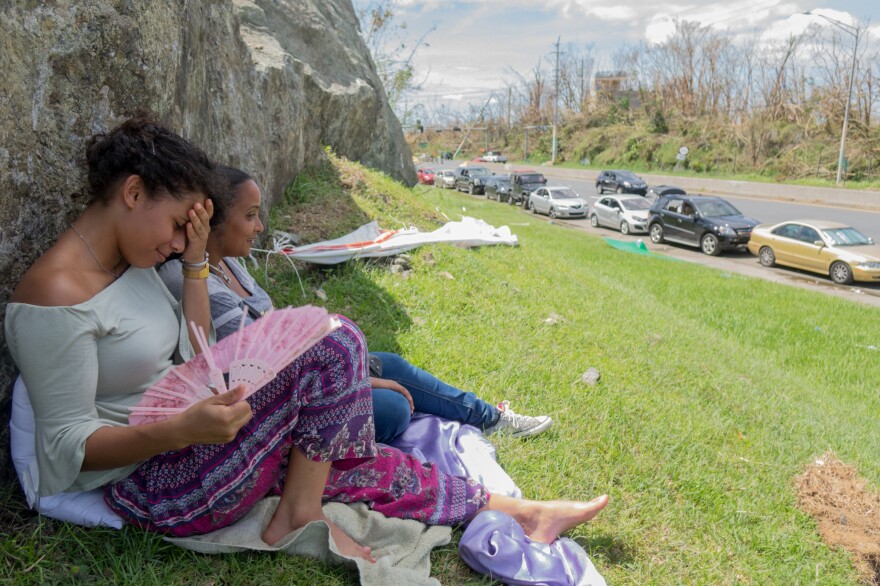 Kiara Rodriguez de Jesus, (left) 23 — with friend Stephanie Norat, 26 — finds shade during her family's 10-plus-hour wait.