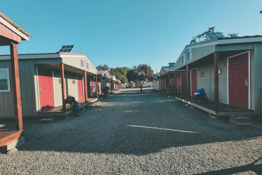 A row of small duplex shelters in a gravel plot