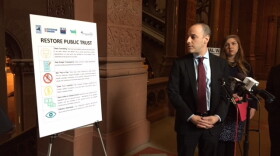 Alex Camarda of Reinvent Albany displays a chart listing potential reforms to clean up state government at a press conference Thursday at the State Capitol.