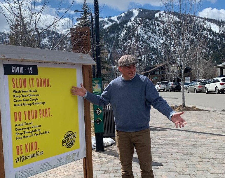 Neil Bradshaw standing next to a sign telling people to be safe during COVID-19