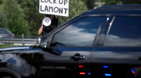 Protestor holds sign that reads "Lock Up Lamont"