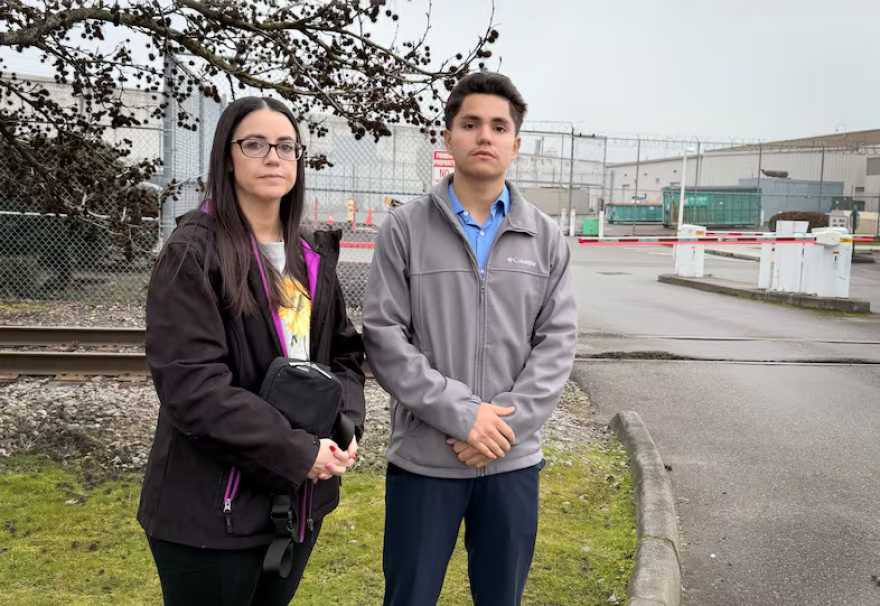 Two people stand outside n ICE detention facility.