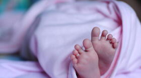 Closeup of the feet of a baby wrapped in a pink blanket
