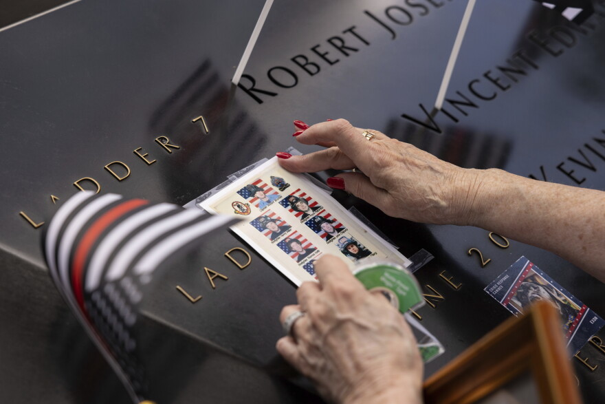 A person puts photos of fallen firefighters on the 9/11 Memorial during the commemoration ceremony on the 22nd anniversary of the September 11, 2001, terror attacks on Monday, Sept. 11, 2023, in New York. (AP Photo/Yuki Iwamura)
