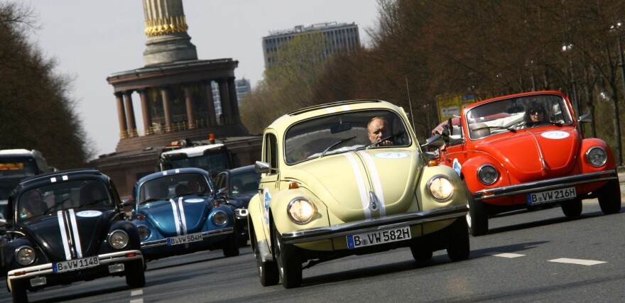 Beetle cars of German car maker Volkswagen (VW) drive past Berlin's landmark the Victory Column on April 23, 2013, in Berlin to promote a new tourist attraction.
