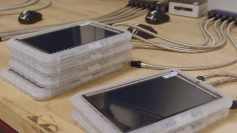 Tablet computers, encased in thick plastic coverings, charge on a table.