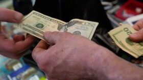 A customer uses cash at a gas station on Monday, March 16, 2026, in Portland, Ore. (AP Photo/Jenny Kane)