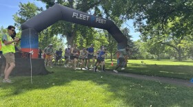 Runners are taking off to run the race after the horn blows, and there is an inflatable above them that says "Fleet Feet".