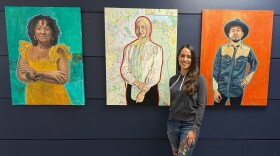 Cristina Fletes-Mach stands in front of her three paintings now on display on the Lower Level at Terminal 1 of St. Louis Lambert International Airport.