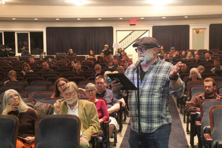 A man speaks into a microphone at a public hearing. 