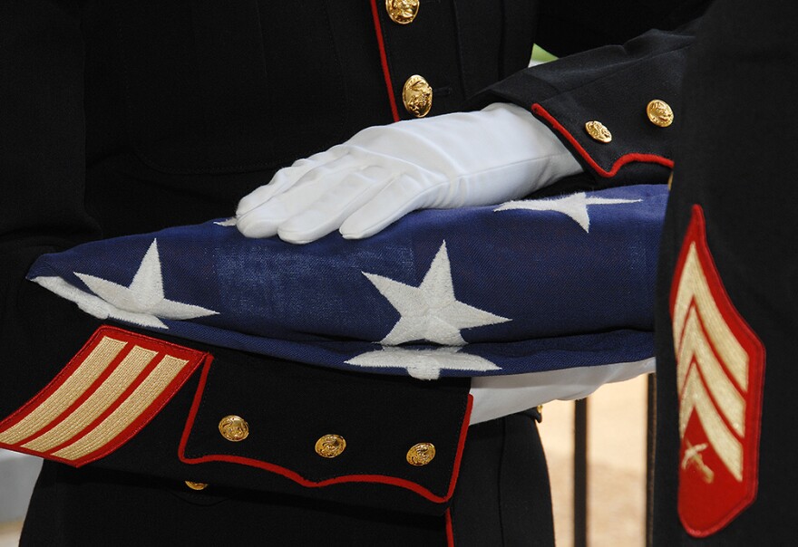 A soldier holding a folded American flag 