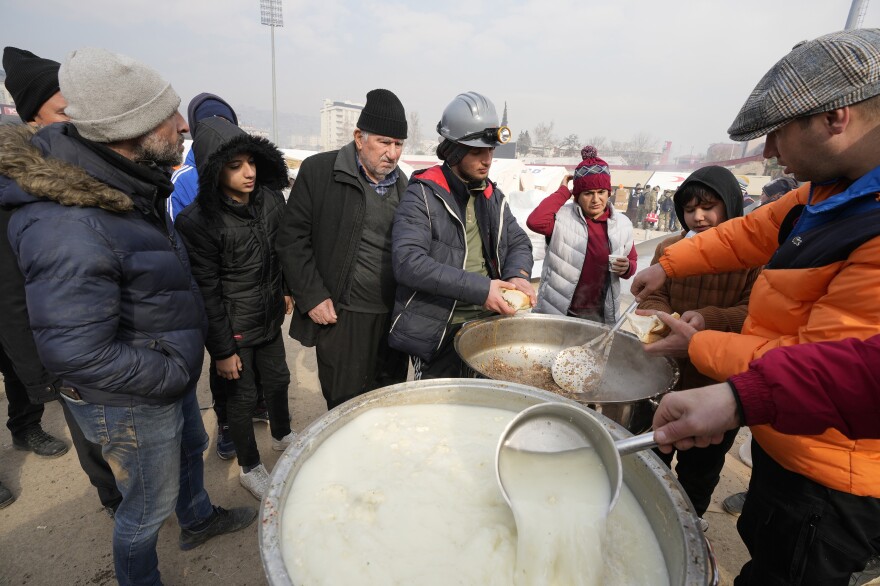 People wait for a meal at a stadium where tents have been setup to accommodate earthquake survivors, in Kharamanmaras, southeastern Turkey. Rescuers pulled several people alive from the shattered remnants of buildings on Friday, some who survived more than 100 hours trapped under crushed concrete in the bitter cold.