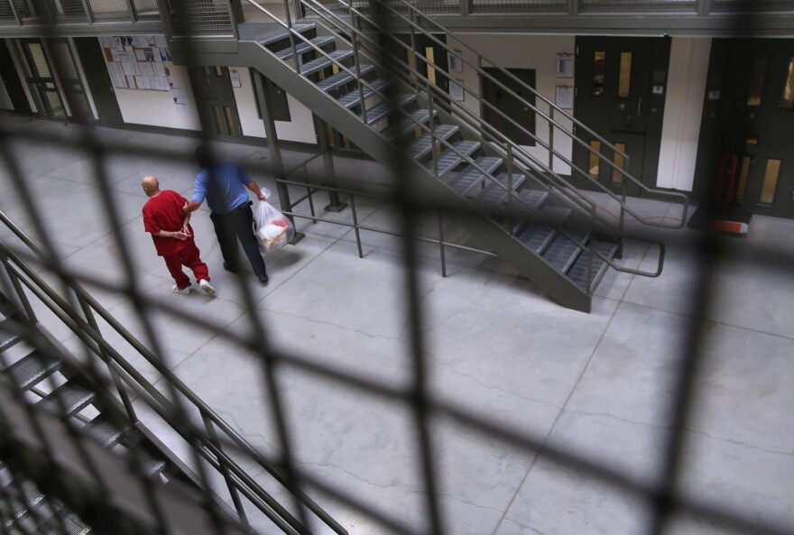 A guard escorts an immigrant detainee from his 'segregation cell' back into the general population at the Adelanto Detention Facility, a private detention center operated by Florida-based GEO Group. (John Moore/Getty Images)