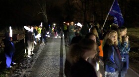 Protestors gather with flags and light-sticks on the road outside of Gov. DeWine's home