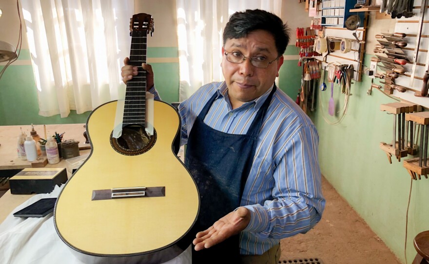 Master guitar maker Arnulfo Rubio Orozco holds up a recent project. It took him a month to craft this guitar with pearl accents and wood from southern Mexico.