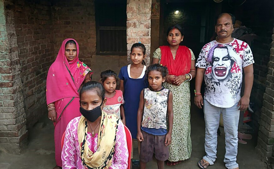 Jyoti Kumari (center, foreground, in mask) and family members stand in front of their house in Sirhulli, a village in eastern India.