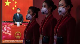 Guides stand near images showing Chinese President Xi Jinping at an exhibition highlighting Xi's years as leader, as part of the upcoming 20th Party Congress in Beijing, China.