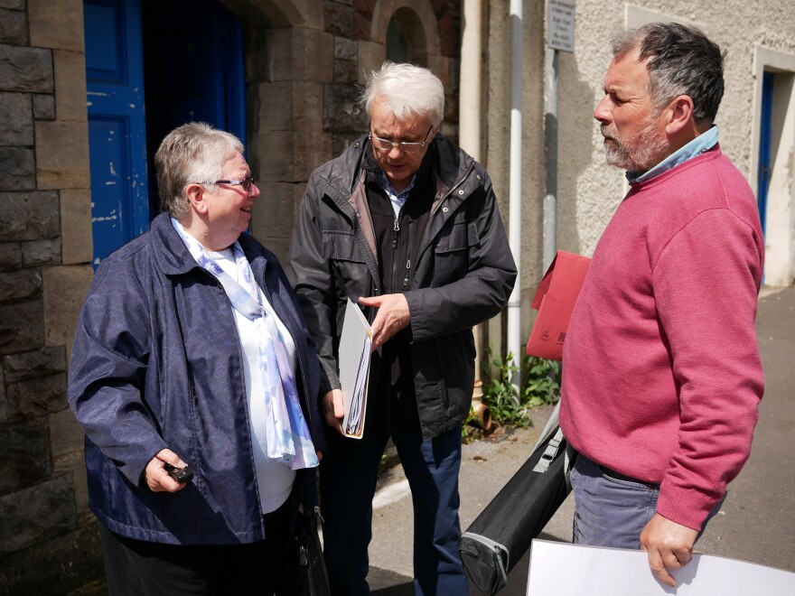 Jeff Britten (center), his wife Sharon and group treasurer Julian Rutter stand outside the Haverfordwest chapel where they organize their work settling Syrian refugees.