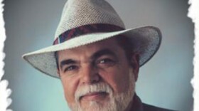 A older man is wearing a suit and a straw hat