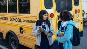 Two students in front of a school bus