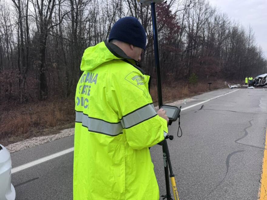 An Indiana State Police trooper investigates near the fatal crash