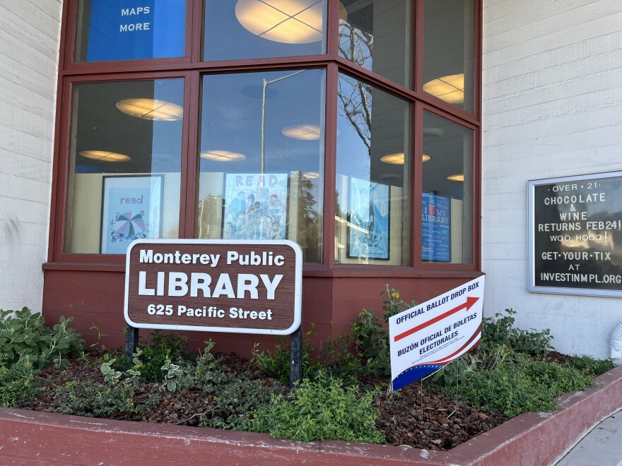 A photo of the Monterey Public Library with a sign reading Official Ballot Box pointing in the direction of the ballot drop box.