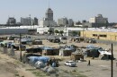 Aerial with of a tent encampment with the Fresno skyline in the background.