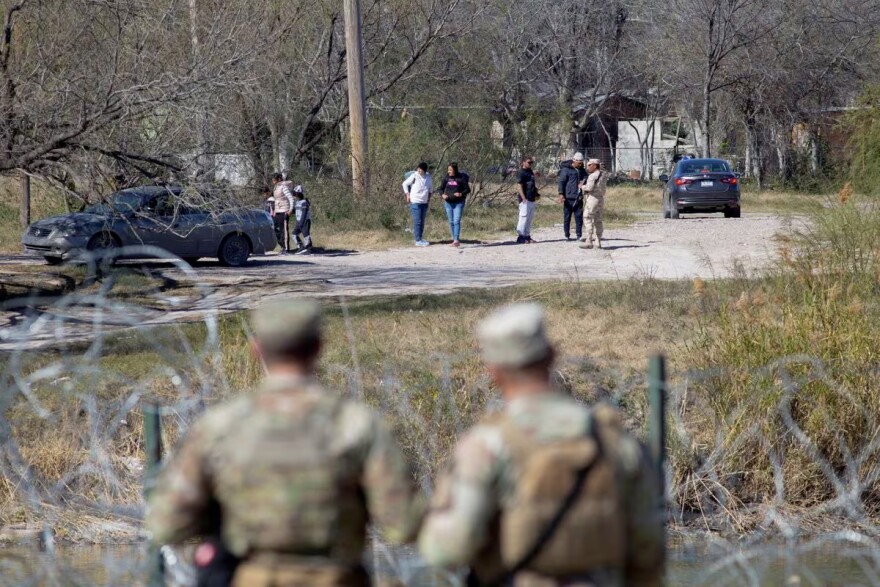  Texas National Guard troops watch a Mexican official prevent a group of people from entering the Rio Grande River across from Shelby Park at the U.S.-Mexico border in Eagle Pass, Texas, U.S., January 12, 2024.