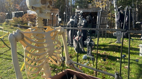 A skeleton stands before a graveyard Oct. 19, 2026, in the ever-expanding Halloween display created by Jeffrey Broking alongside family members on Crystal Springs Loop, south of Grand Rapids.