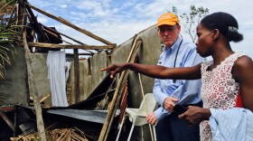 Dr. Paul Farmer, co-founder of Partners In Health, stands with Mirlande Estenale in front of what used to be her home in the town of Les Cayes, Haiti.