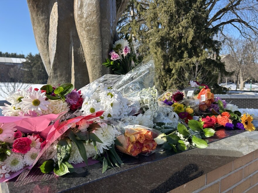 Flowers cover the base of the Spartan statue outside Spartan Stadium in honor of the 2023 campus shooting victims.