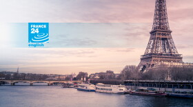 A beautiful wide shot of Eiffel Tower in Paris surrounded by water with ships under the colorful sky